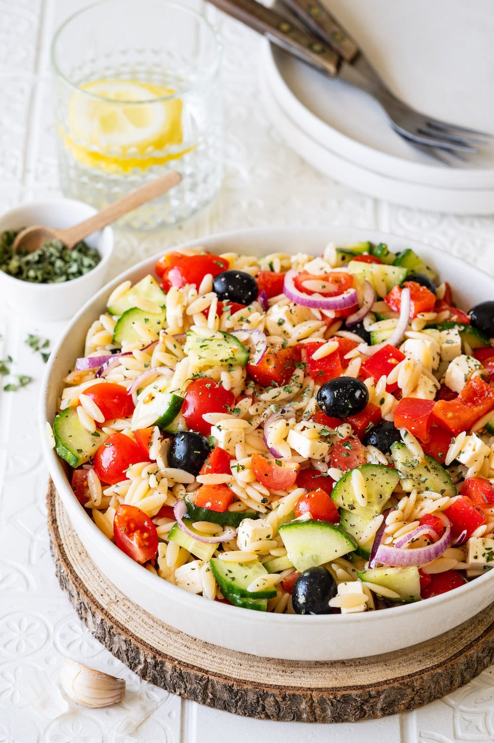 Griechischer Kritharaki-Salat mit Oliven, Tomaten, Paprika, Gurken, Feta und Zwiebeln in einer Schüssel angerichtet.