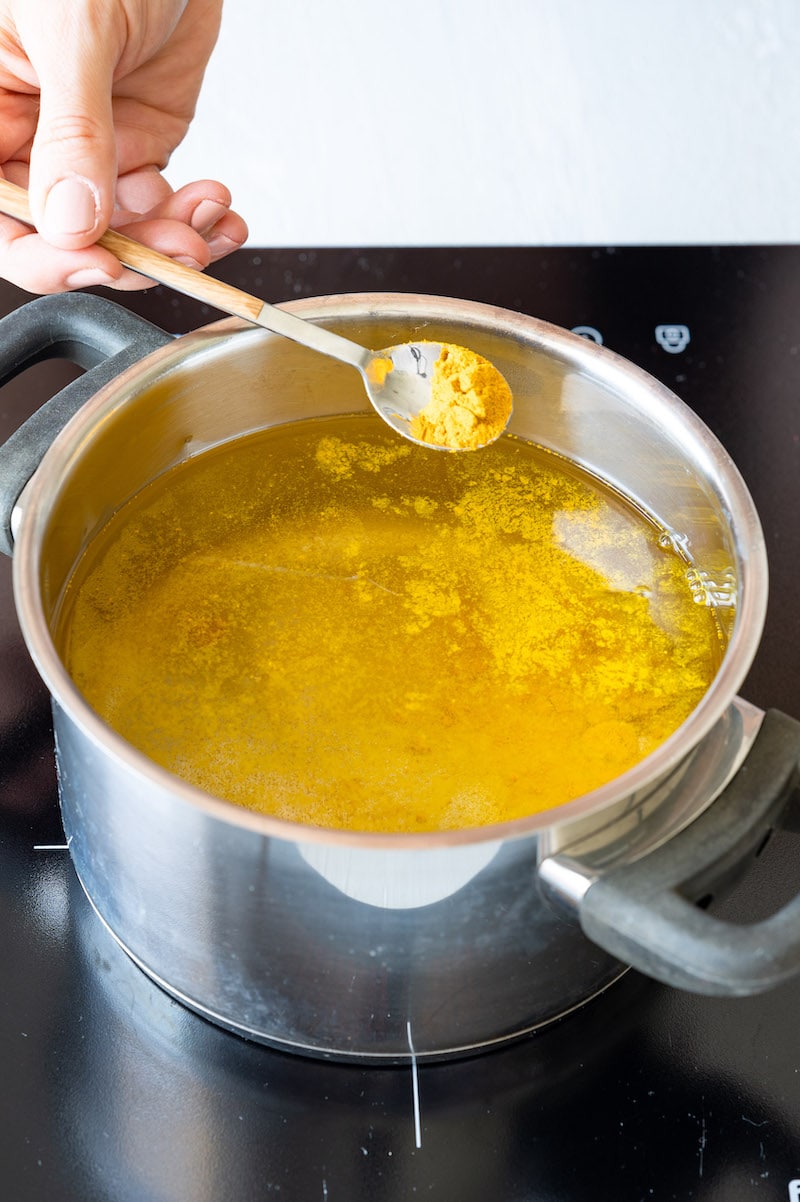 Currypulver wird in einen Topf mit Wasser gegeben.