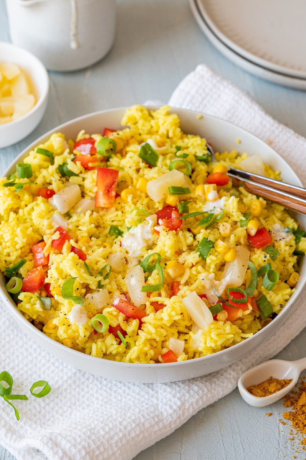 Reissalat mit Curry, Ananas, Mais und Paprika in einer weißen Schüssel serviert.