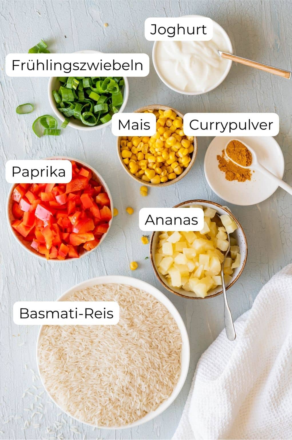 Zutaten für den Reissalat in Schüsselchen: Basmati-Reis, rote Paprika, Ananas, Mais, Frühlingszwiebeln, Joghurt und Currypulver.