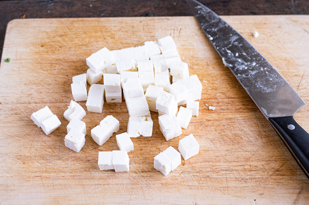 Feta auf einem Schneidbrett in kleine Würfel geschnitten.
