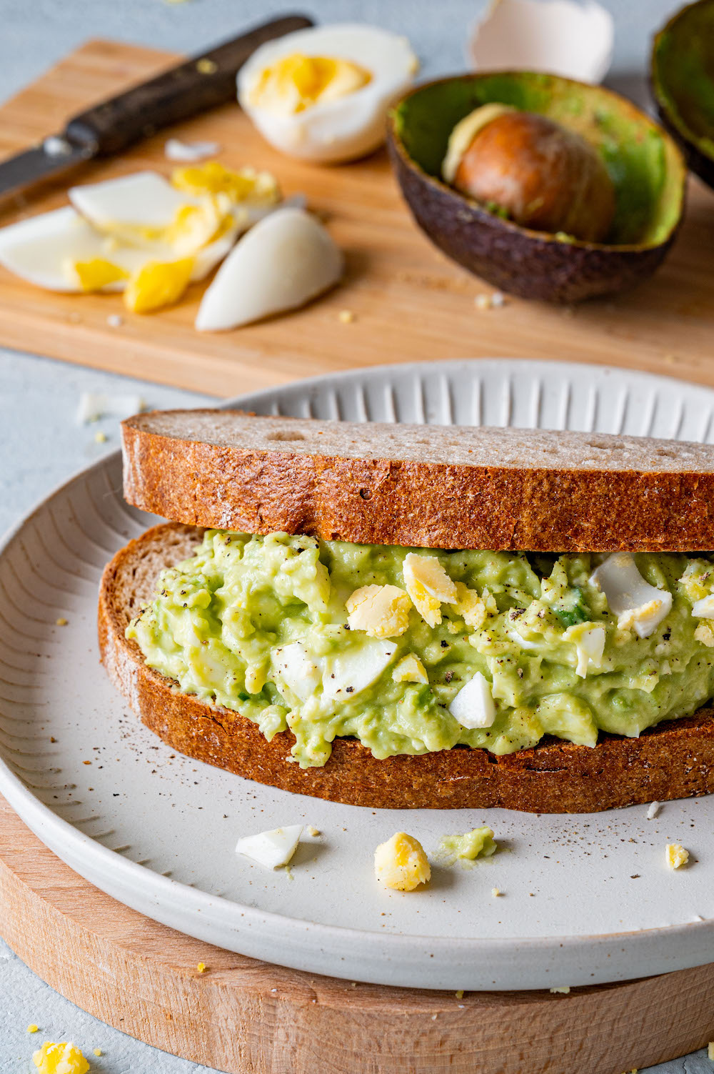 Ein Sandwich aus zwei Brotscheiben ist zwischendrin dich mit dem Avocado-Eier-Salat bestrichen.